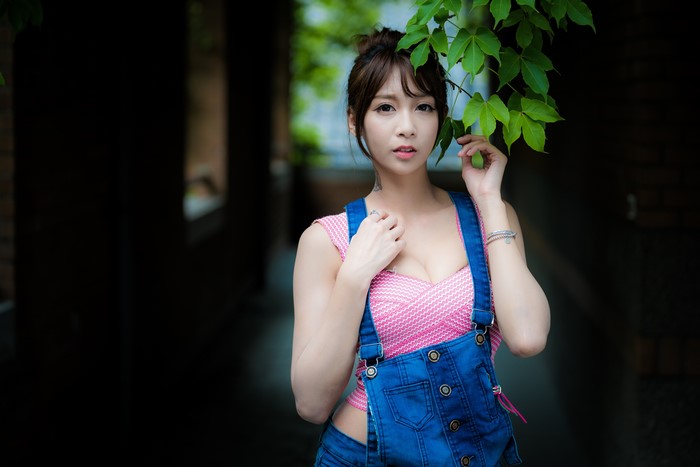 Asian woman in pink top and denim overalls