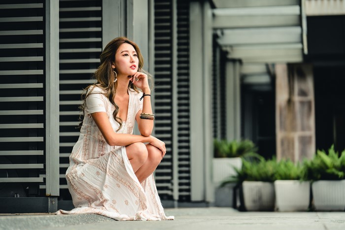 Asian woman in a dress crouching outdoors