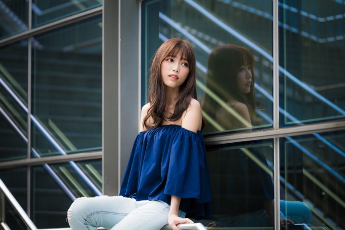 Asian woman with brown hair sitting by a window