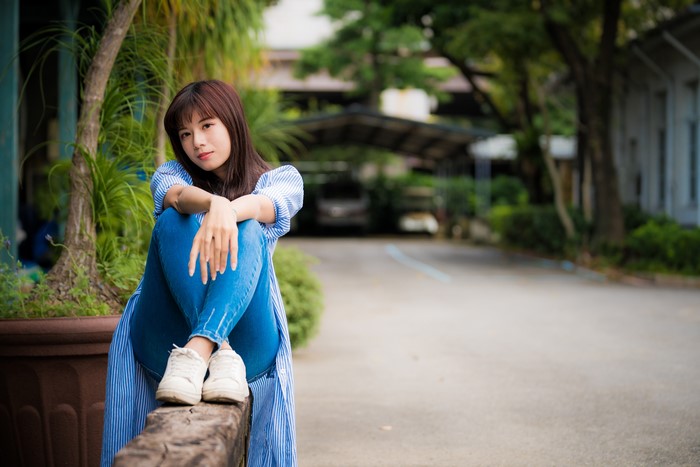 Asian woman with brown hair sitting outdoors