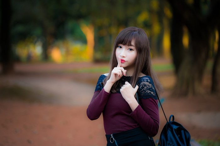 Asian woman with brown hair making a shushing gesture