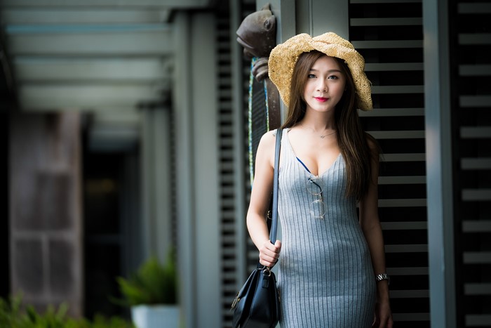 Asian woman with brown hair wearing a straw hat and dress