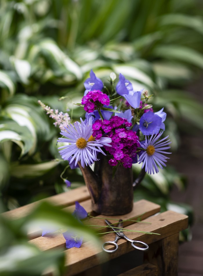 Bouquet of purple and blue flowers in a watering can vase