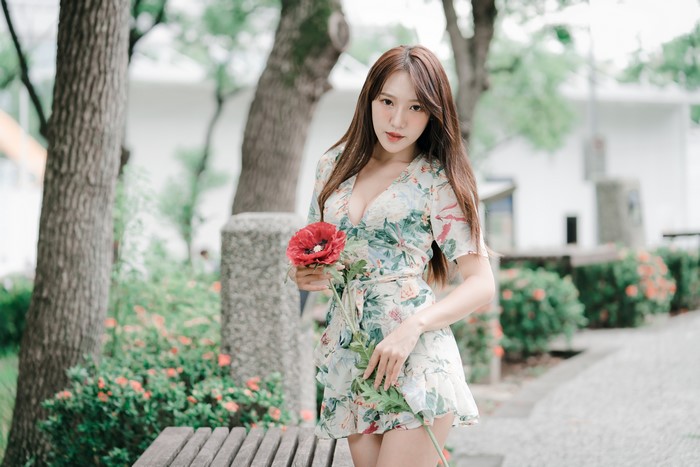 Asian woman in floral dress holding a red flower