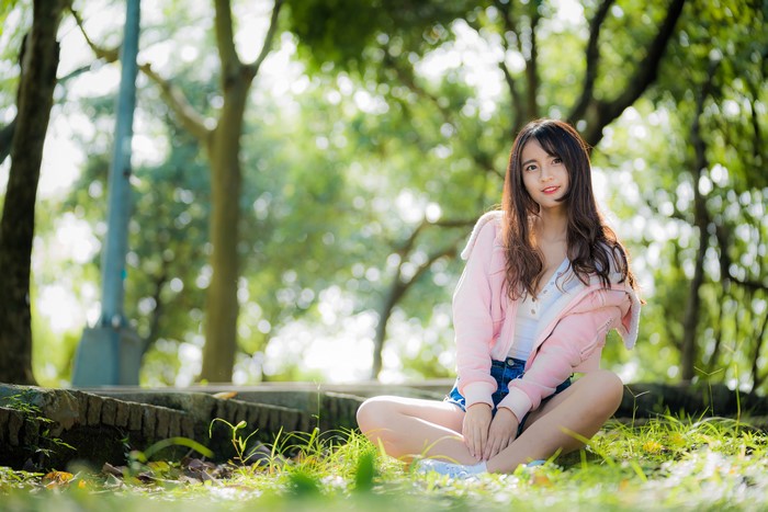 Asian girl with brown hair sitting on grass