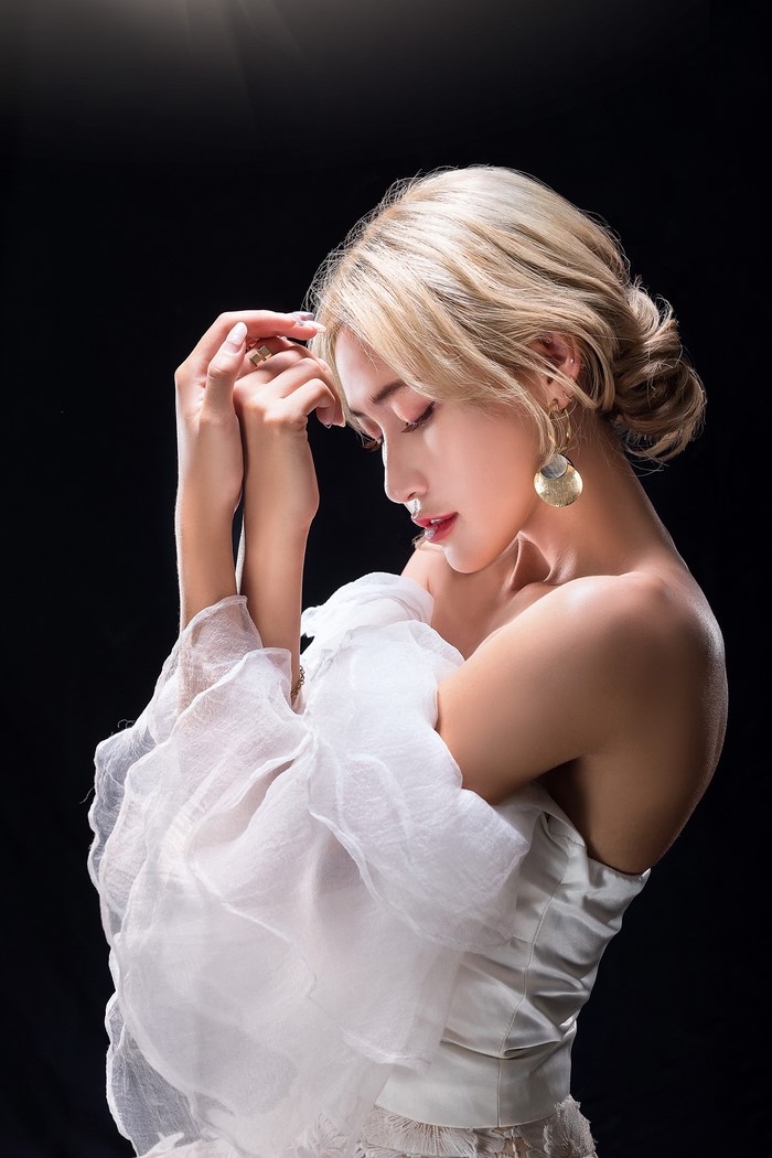 Asian blonde woman in white dress with large earrings