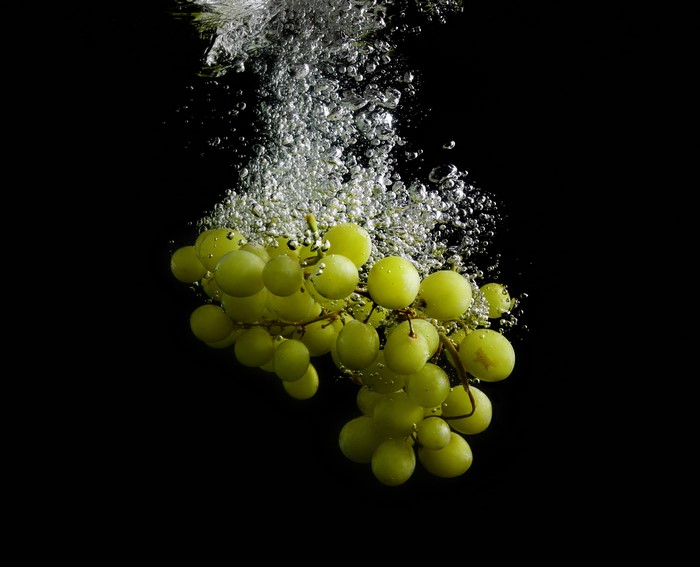 Green Grapes Dropping in Water with Bubbles