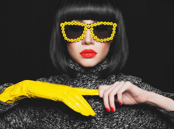 Woman with flower-decorated glasses and yellow glove