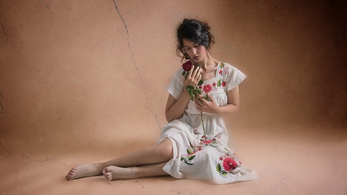 Woman in embroidered dress holding a rose