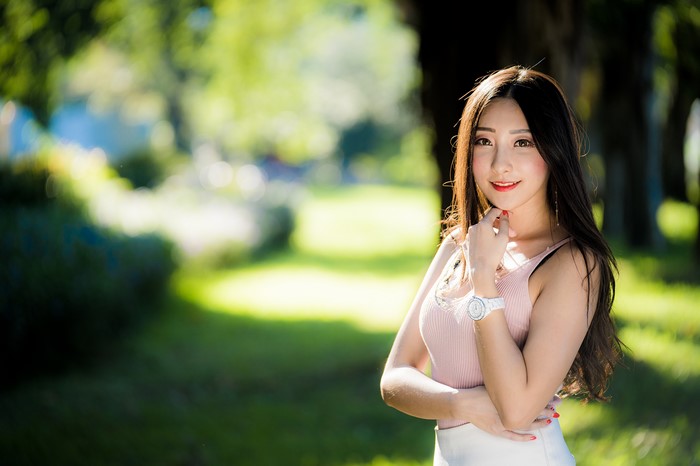 Asian woman in pink singlet smiling in park