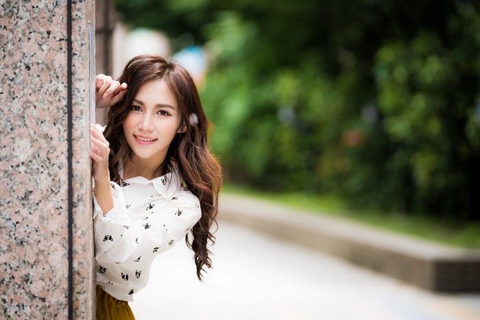 Asian Woman Smiling Behind a Column