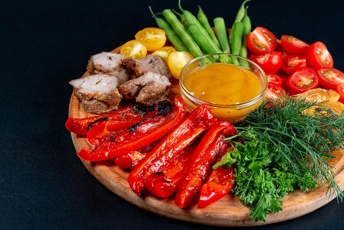 4K platter of grilled pork, bell peppers, tomatoes, and green beans