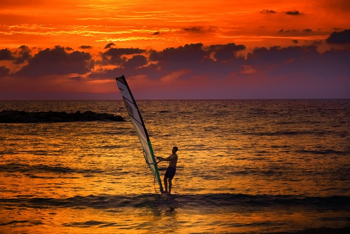Man windsurfing at sunset
