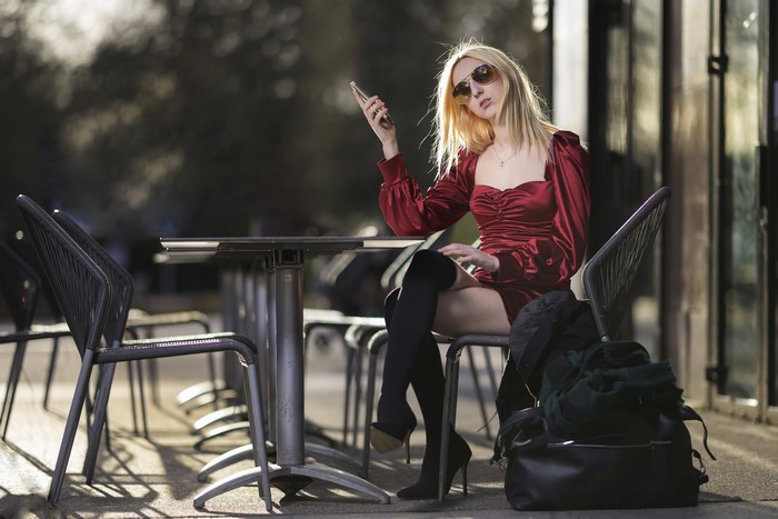 Blonde woman in red dress sitting at cafe table