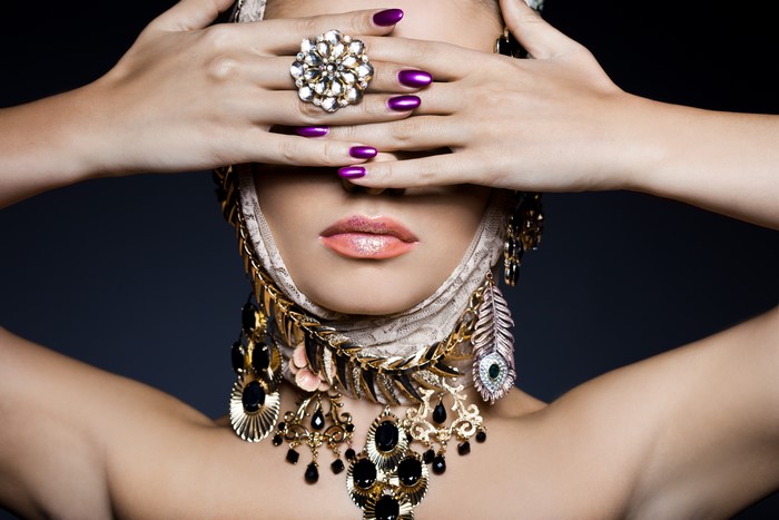 Woman with elaborate jewelry and purple manicure