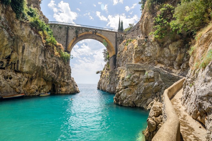 Arched bridge over a turquoise cove in Italy