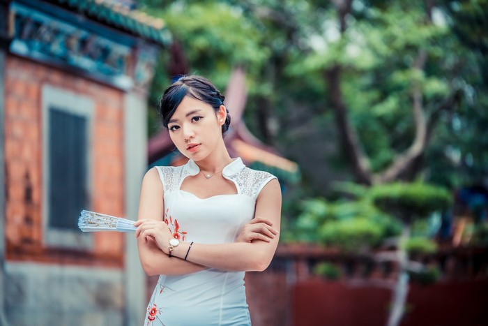 Asian woman in white dress holding a fan