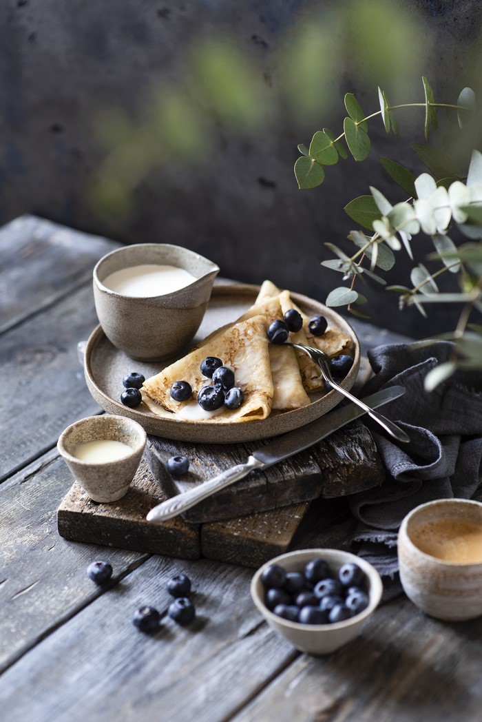 Pancakes with blueberries and cream on wooden planks