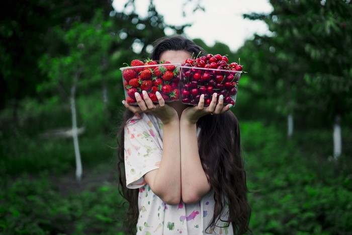 Girl holding boxes of strawberries and cherries