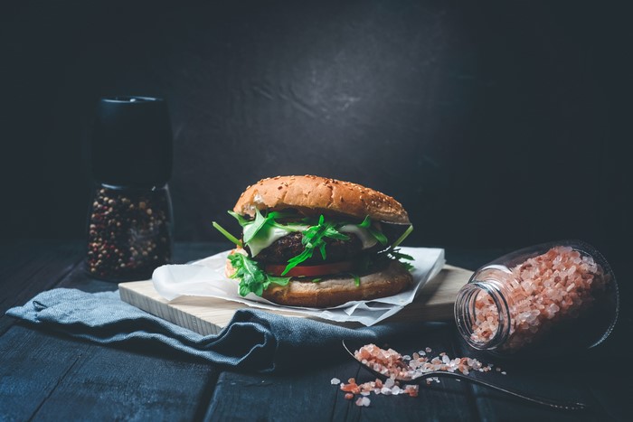 Hamburger with salt and pepper shakers on wooden table