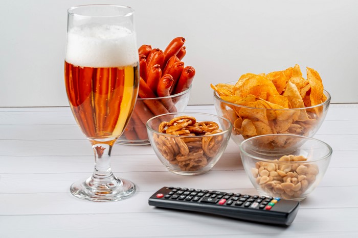 Beer, sausages, chips, pretzels, nuts, and remote