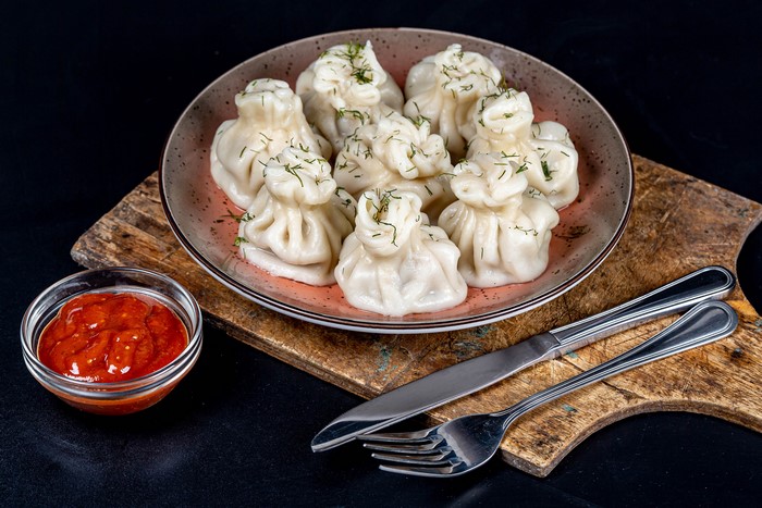 Khinkali dumplings with dill and ketchup on a cutting board
