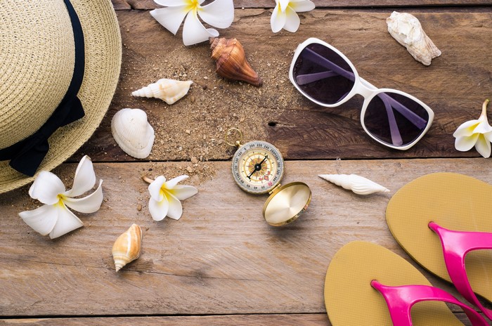 Beach accessories on wooden planks with shells and flowers
