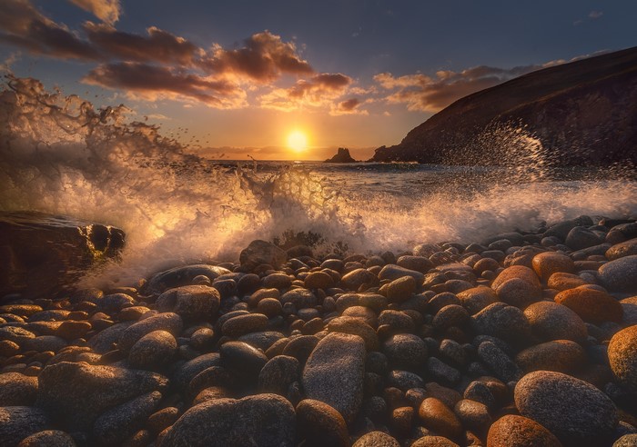 Waves crashing on a rocky beach at sunset