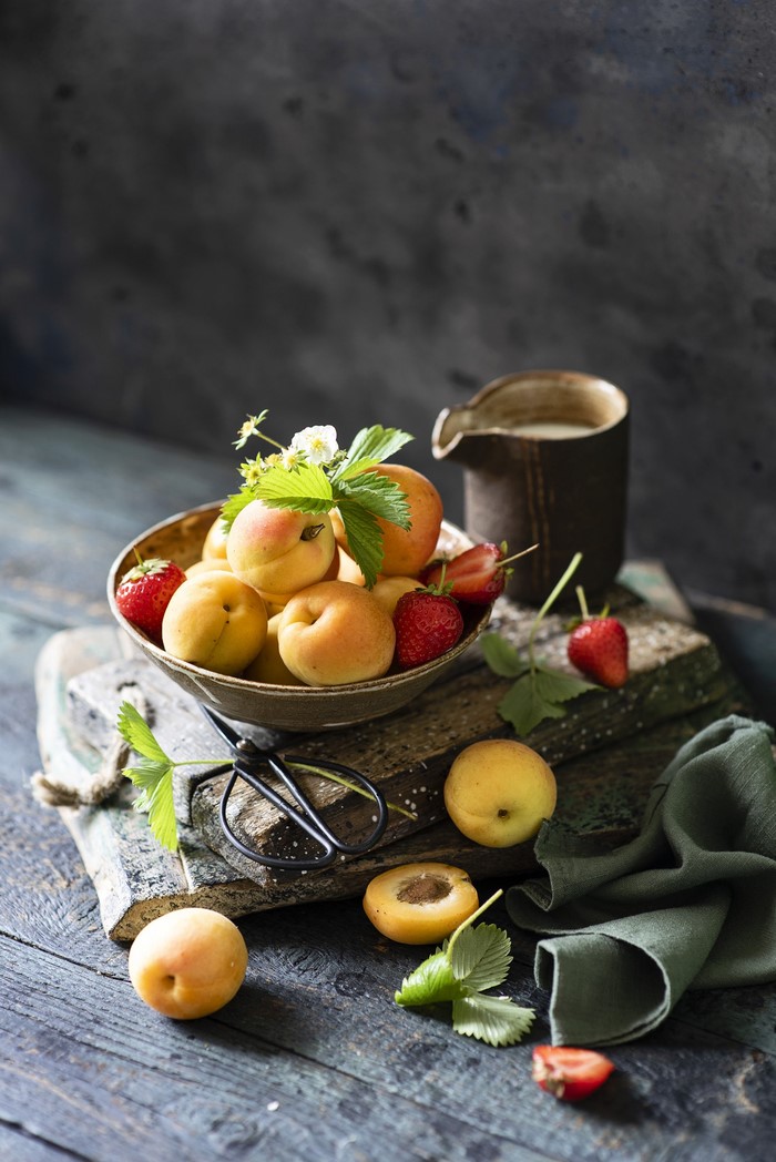 Apricots and strawberries in a bowl with a pitcher
