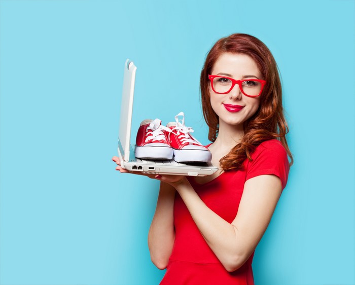 Redhead girl with red glasses holding laptop with red shoes