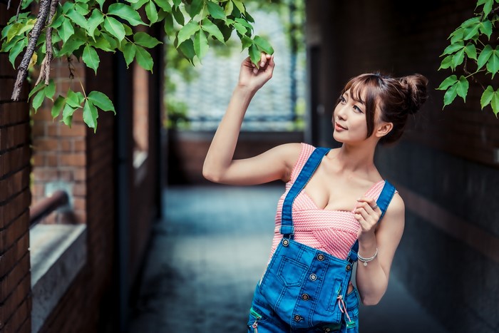Asian woman in overalls touching leaves