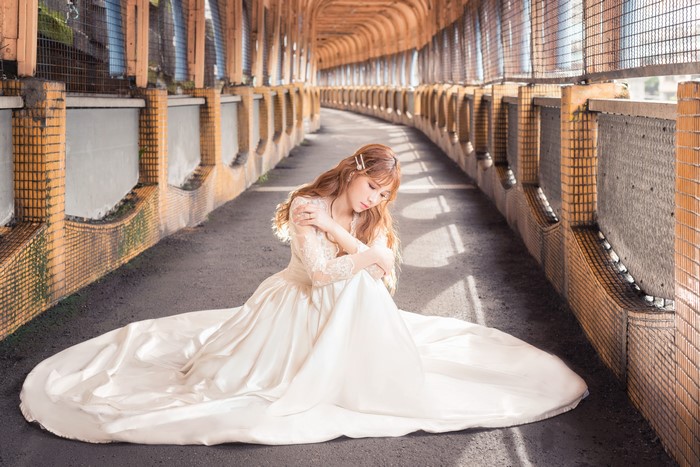 Asian woman in white dress sitting in a tunnel