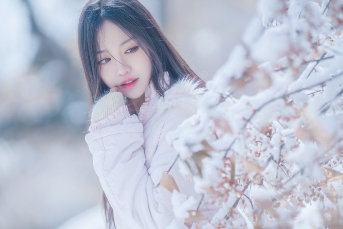 Asian woman in snow with branches
