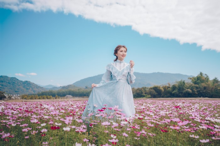 Woman in a blue dress in a field of cosmos flowers