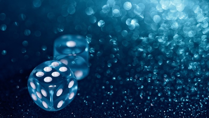 Two translucent blue dice on a dark sparkly surface