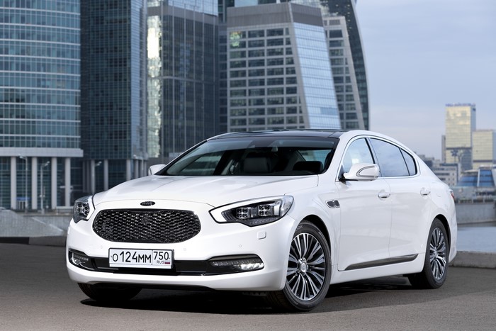 White Kia K900 Sedan with City Buildings