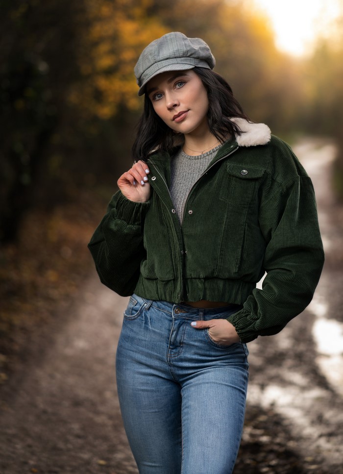 Brunette girl in jeans and jacket wearing a cap