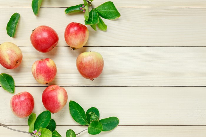 Apples with leaves on a wooden surface