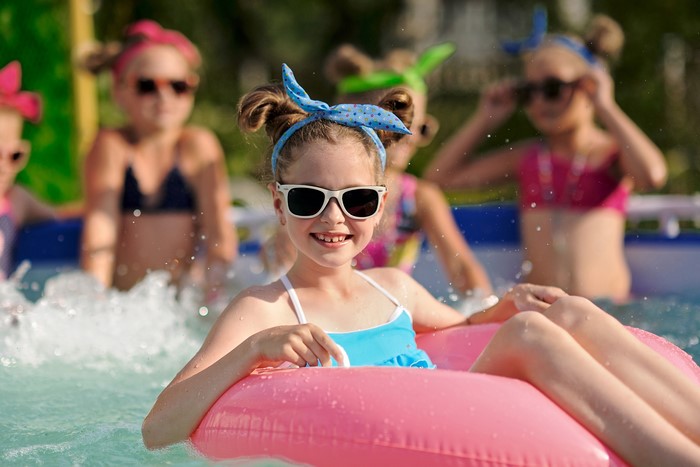 Girls in sunglasses playing in a pool with inflatable rings
