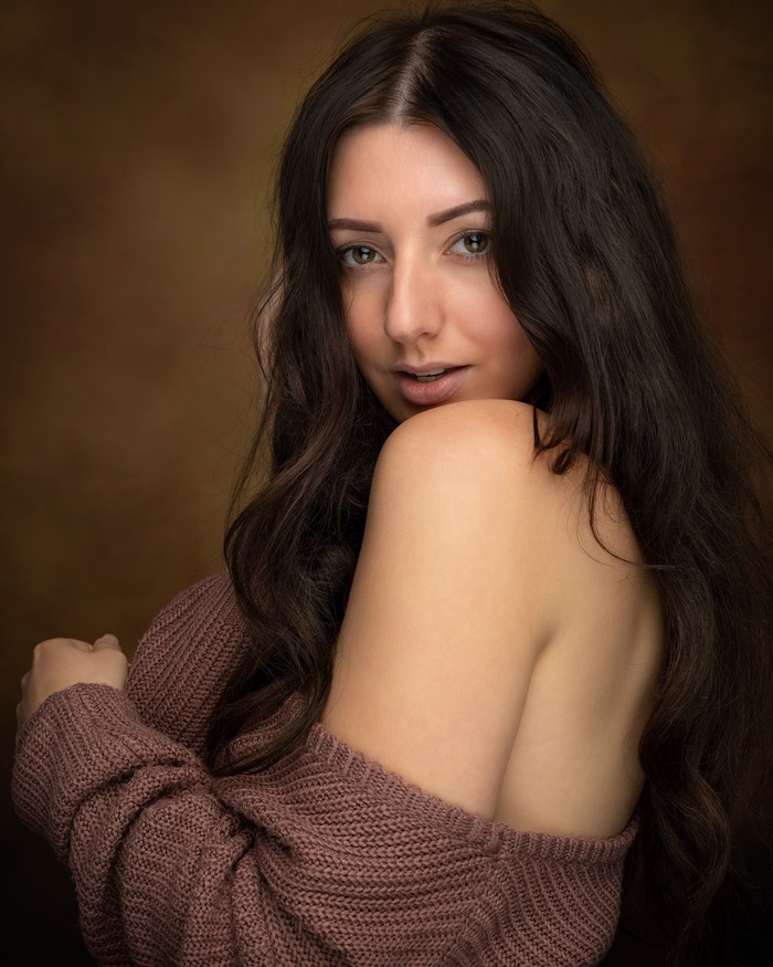 Brunette woman in a sweater looking over her shoulder