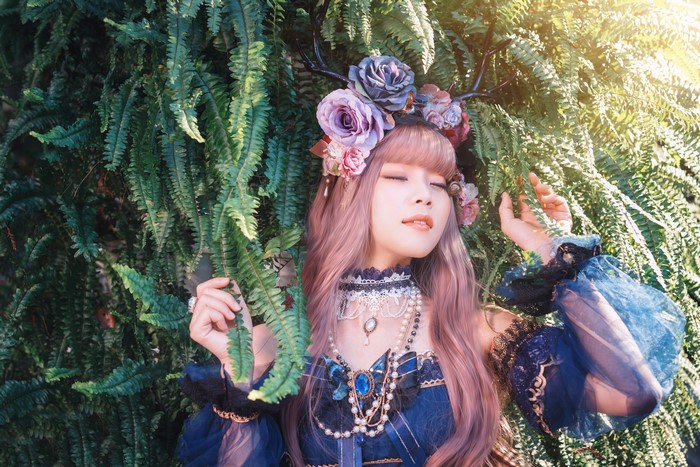 Asian girl with flowers and antlers in ferns