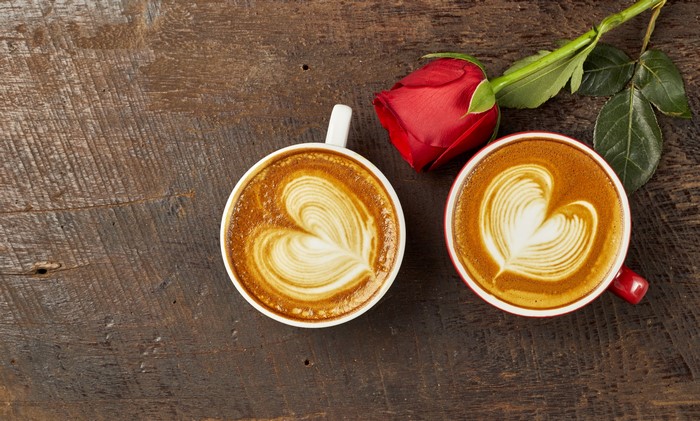 Two coffees with latte art and a red rose