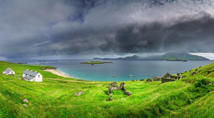 Ruined buildings on a green coast in Ireland under thunderclouds