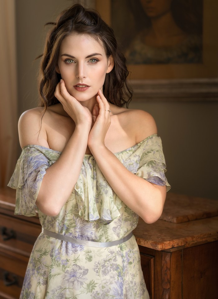 Woman in a floral dress with hands near face
