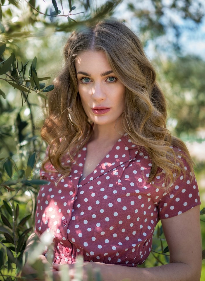 Woman with dark blonde hair in a polka dot dress
