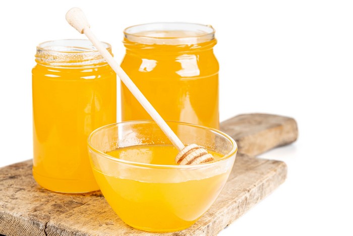 Honey in jars and bowl on cutting board