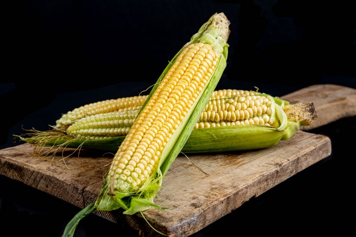 Two ears of corn on a cutting board