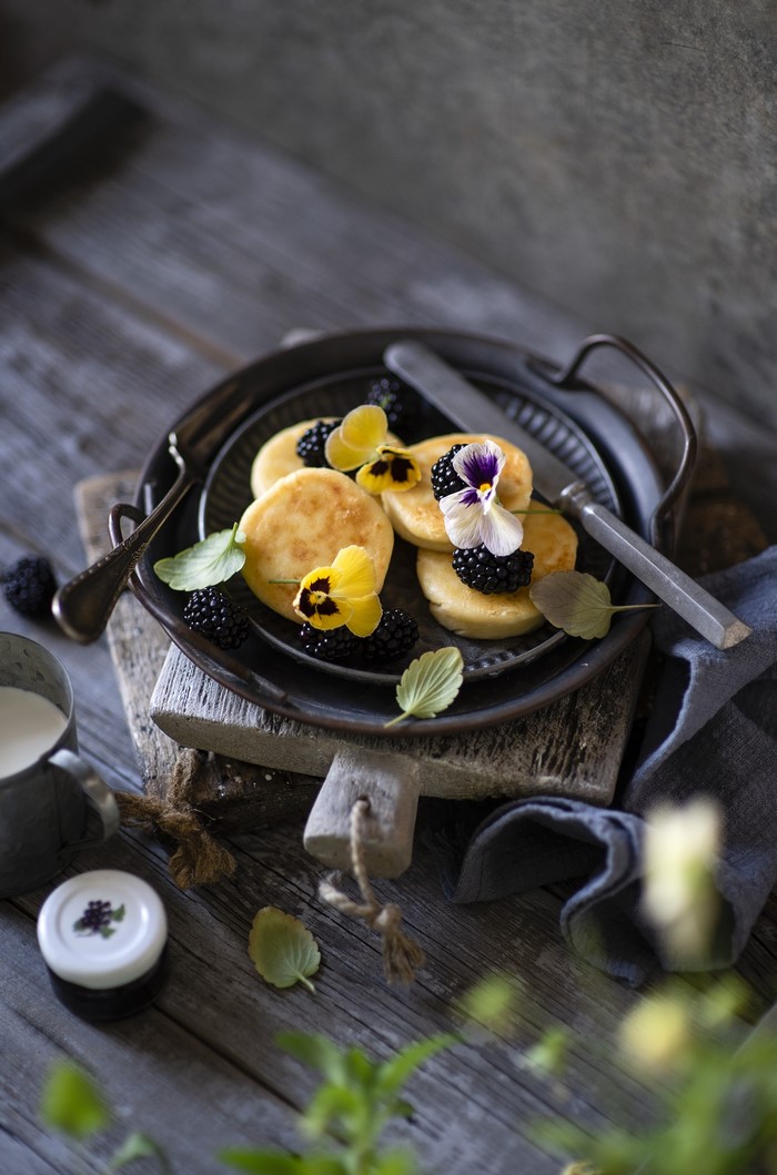 Pancakes with blackberries and pansies on a tray