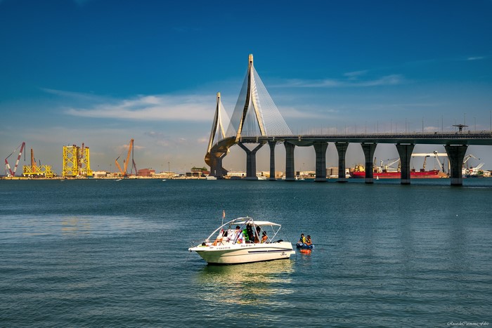 Boat on water with bridge and industrial background
