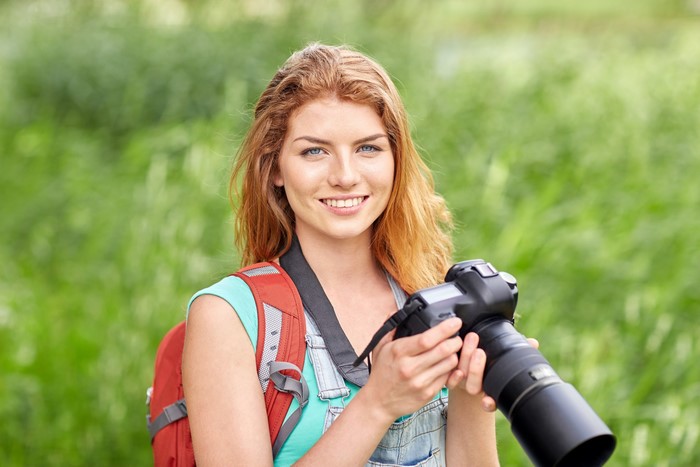 Redhead girl with camera and backpack
